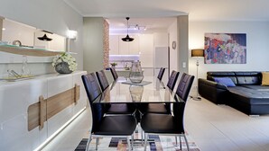 A modern living room with a glass dining table, black leather chairs, a black leather sofa, and a colorful abstract painting on the wall. - Vilamoura Design With Pool by Homing (Loulé)