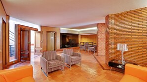 A spacious lobby with a brick accent wall, multiple seating areas, and a staircase leading to upper floors. - Vilamoura Design With Pool by Homing (Loulé)