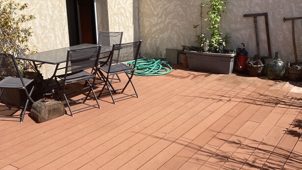 Un patio con una mesa, sillas, una planta en maceta y una manguera.
