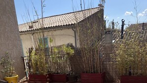 An outdoor patio area with a tiled floor, a striped table, and several potted plants. - Appartement Climatisé Avec Terrasse à Vidauban (Vidauban)
