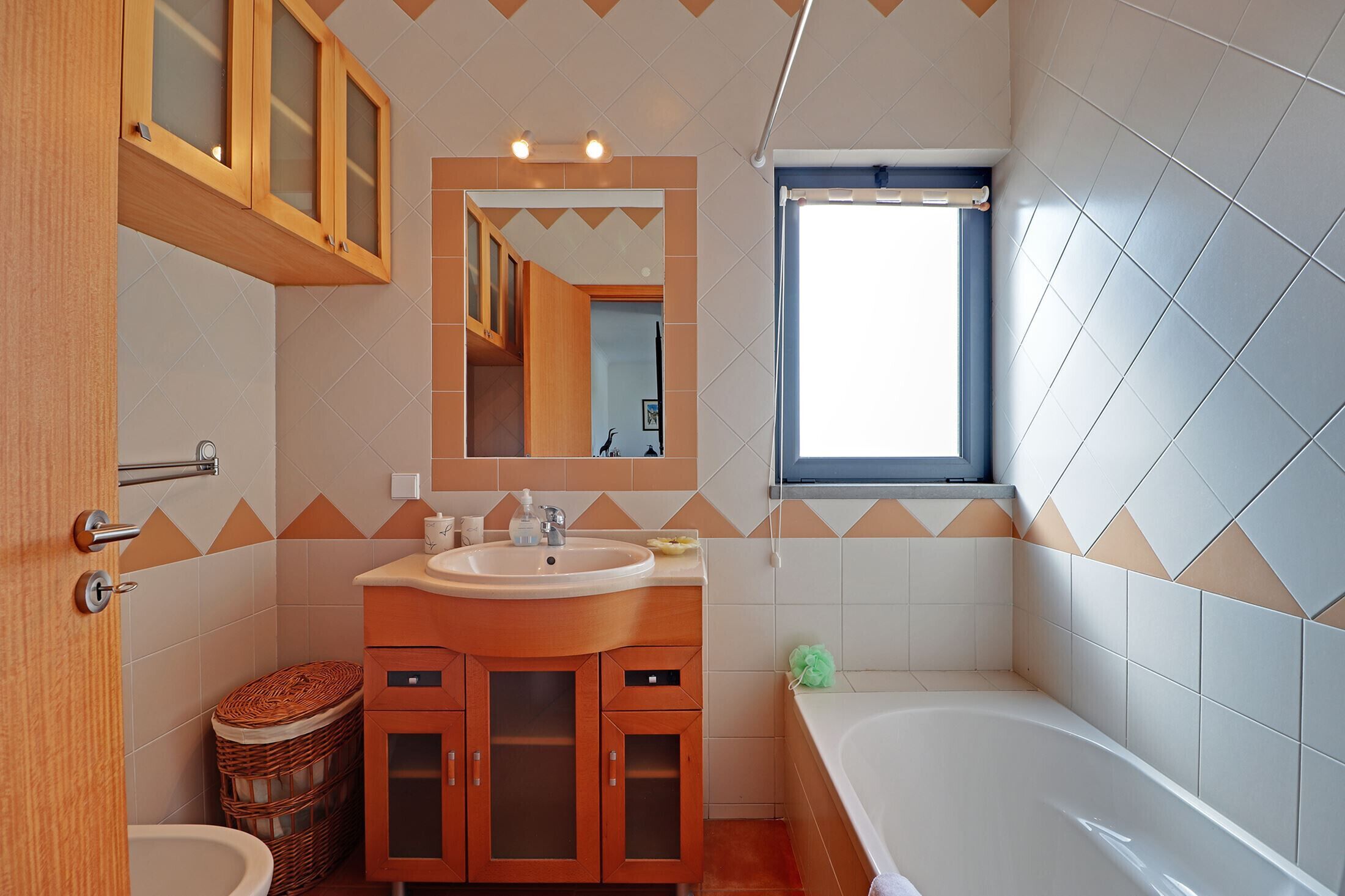 A bathroom with a wooden vanity, a sink, a mirror, and a bathtub.