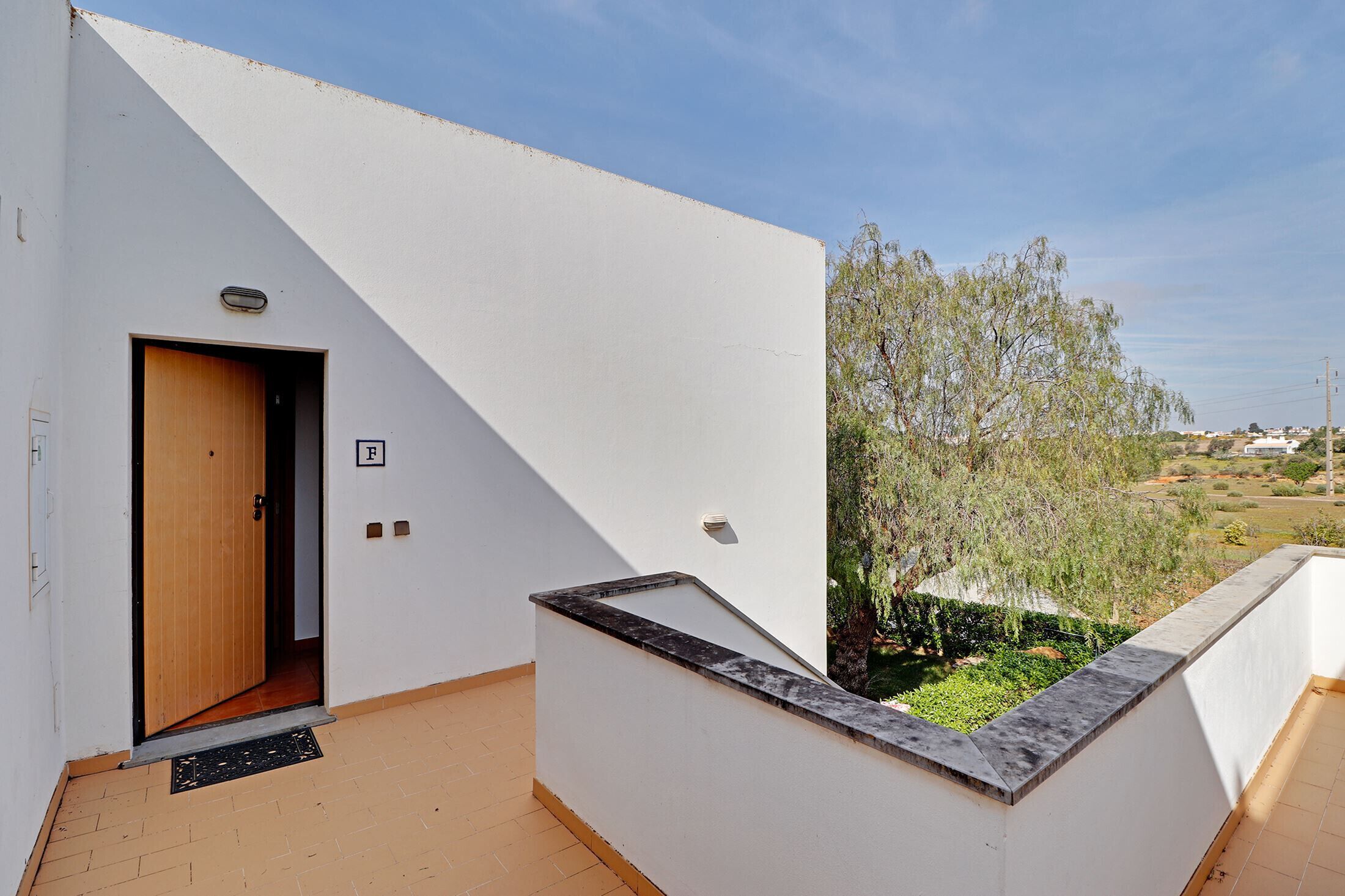 A modern building with a white exterior, a wooden door, and a small balcony with a stone ledge.