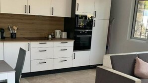 Eine moderne Küche mit weißen Schränken, einem eingebauten Ofen und einem Essbereich mit einem grauen Tisch und Stuhl.