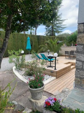 A wooden deck with outdoor furniture, a potted plant, and a stone wall. - Gite Palmier (Mougins)