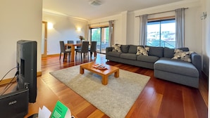 Uma sala de estar moderna com sofá, mesa de centro e área de jantar.