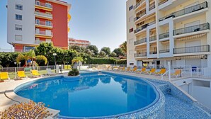 A swimming pool with a tiled edge, surrounded by lounge chairs and a fence. - Armação DE Pera Central by Homing (Silves)