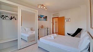 A bedroom with a bed, a wardrobe, a chair, and a painting on the wall. - Armação DE Pera Central by Homing (Silves)