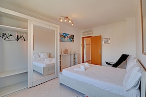 A bedroom with a bed, a wardrobe, a chair, and a painting on the wall. - Armação DE Pera Central by Homing (Silves)