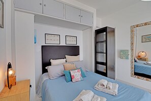 Ein Schlafzimmer mit Bett, Nachttisch, Spiegel und Kleiderschrank.