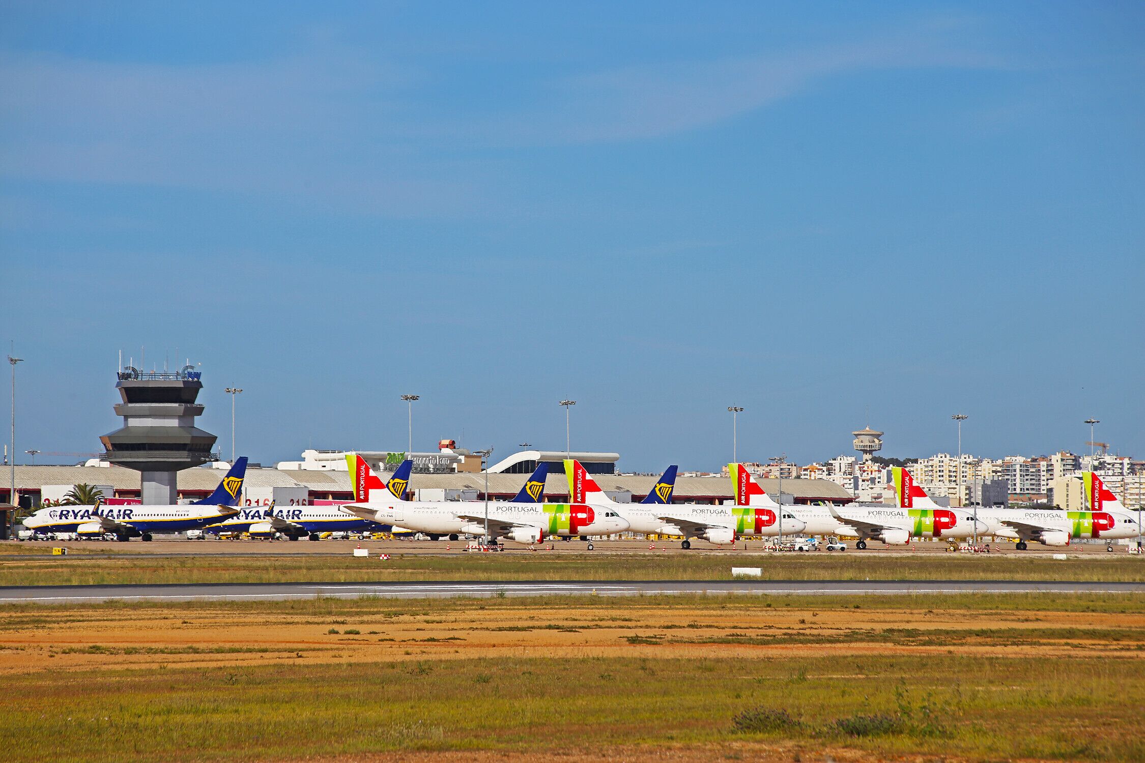 Egy repülőtér, ahol több repülőgép parkol, köztük a Ryanair és a Portugal Air gépei is.