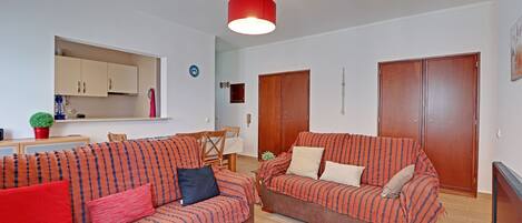 Ein Wohnzimmer mit zwei Sofas, einem Esstisch und einer Küchenzeile.