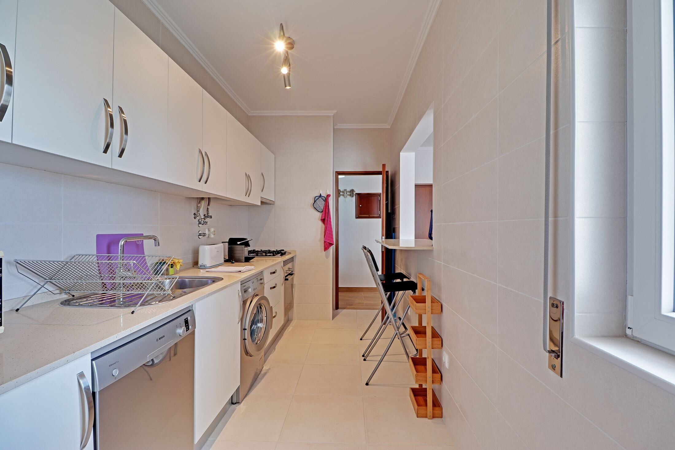 A modern kitchen with white cabinets, stainless steel appliances, and a compact layout.