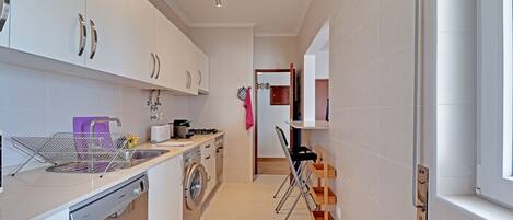 A modern kitchen with white cabinets, stainless steel appliances, and a compact layout.