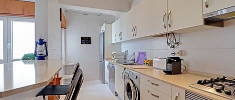 A modern kitchen with white cabinets, a built-in washing machine, and a gas stove.