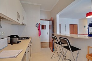 A modern kitchen with a gas stove, a toaster, and a sink. There are two chairs near the kitchen counter. - Portimão Marina View by Homing (Portimão)