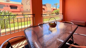 Un balcó amb una taula de vidre, cadires i una cistella de fruita.