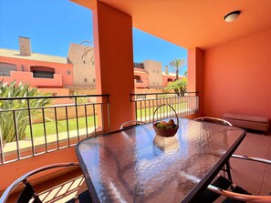 A balcony with a glass table, chairs, and a fruit basket. - Vilamoura Victoria Gardens With Pool (Loulé)