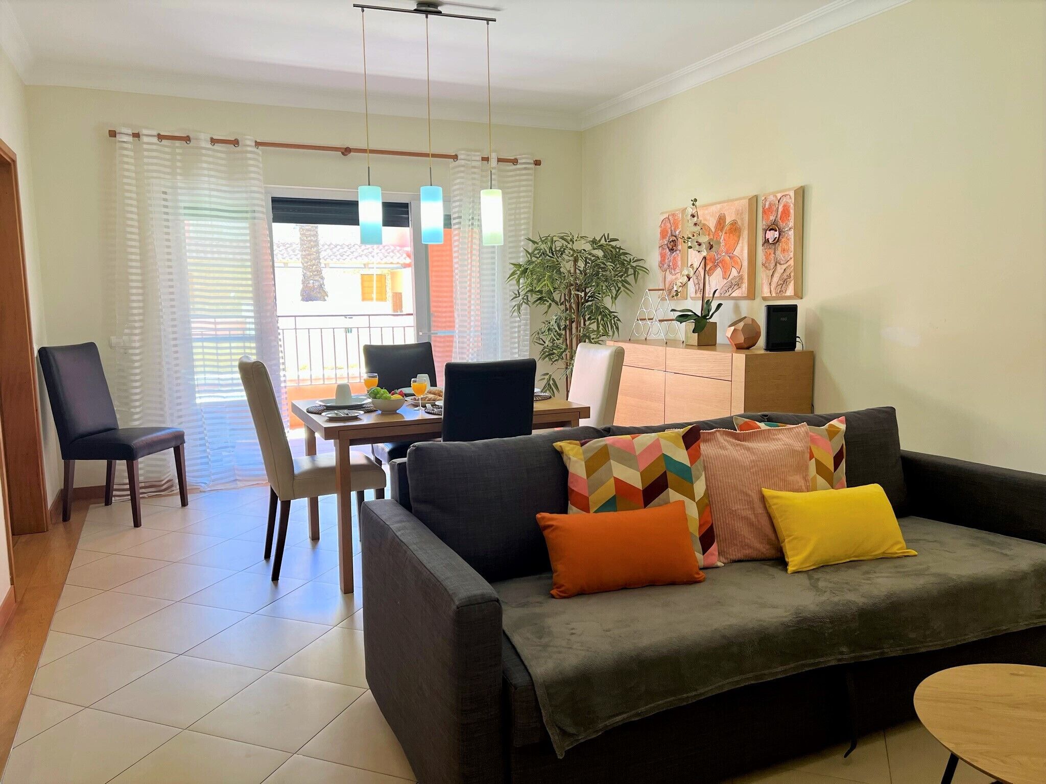 Una sala de estar con sofá, sillas, una mesa de comedor y un balcón con vistas.