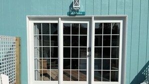 A teal building with a double door entrance, a doormat, and a sign above the door.