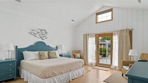 A bedroom with a bed, nightstands, a window, and a door leading to an outdoor area.