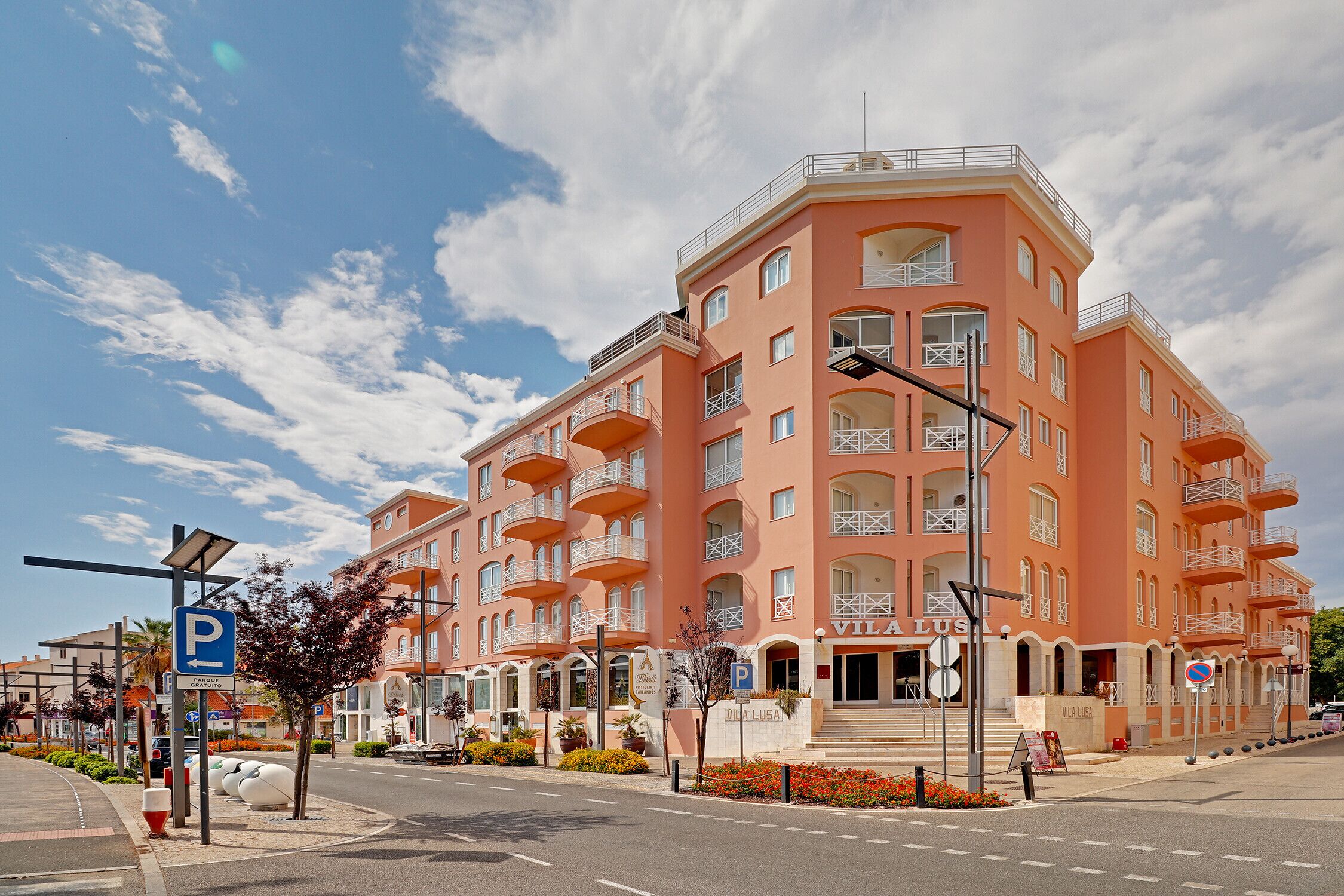 Un hôtel à plusieurs étages doté de balcons, d’un panneau indiquant un parking et surplombant un ciel dégagé.