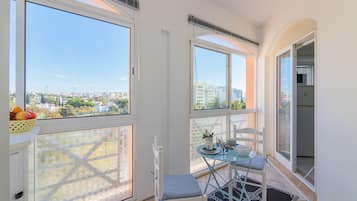 A balcony with a table, chairs, and a fruit basket.