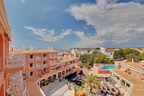 Ein Hotel mit mehreren Balkonen, einem Schwimmbad und einem Innenhof mit Außenbestuhlung.