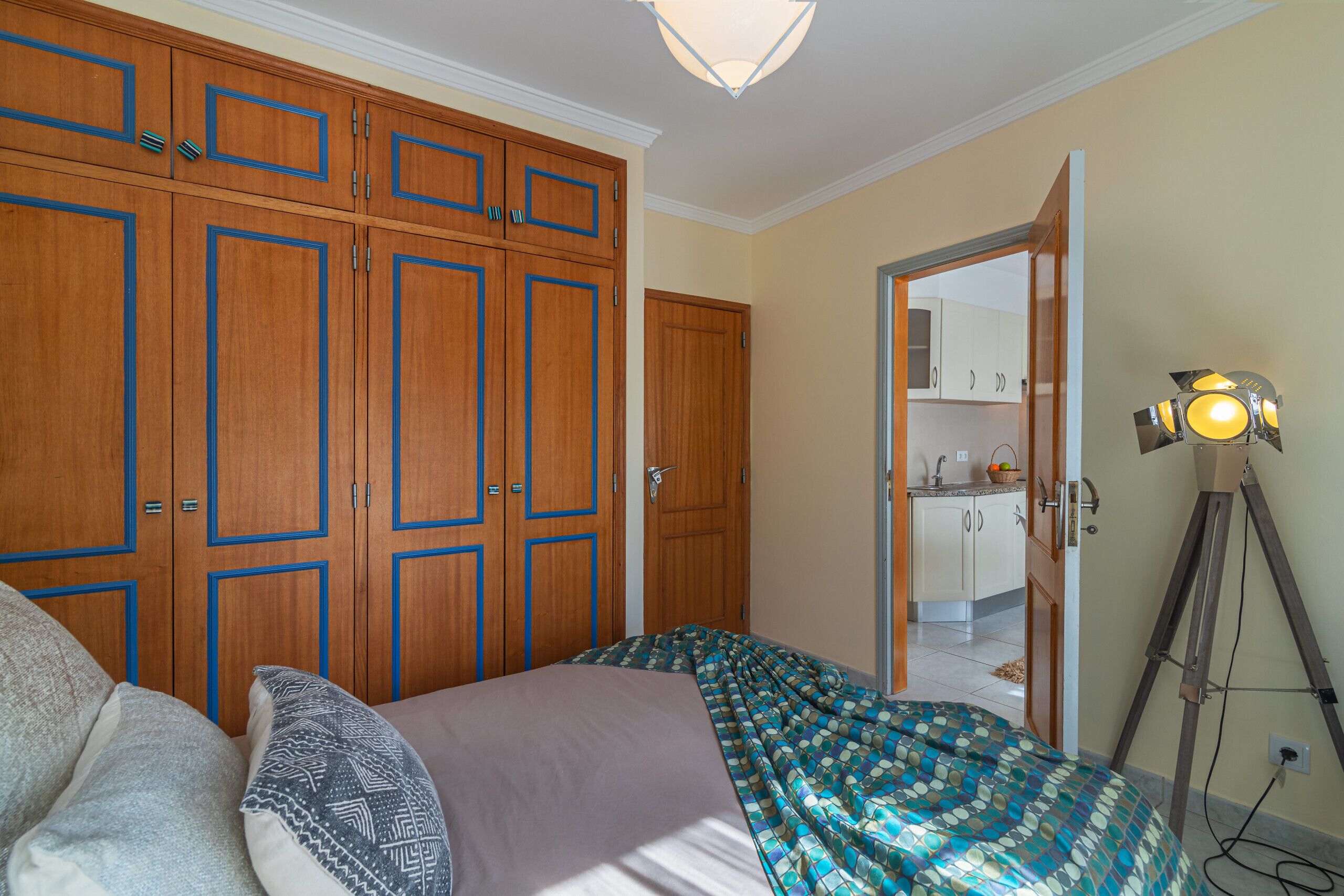 A bedroom with a bed, a wardrobe, and a desk lamp.