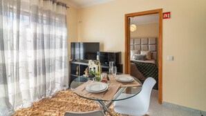 Ett modernt hotellrum med ett glasbord, en soffa, en TV och en säng med en sänggavel.