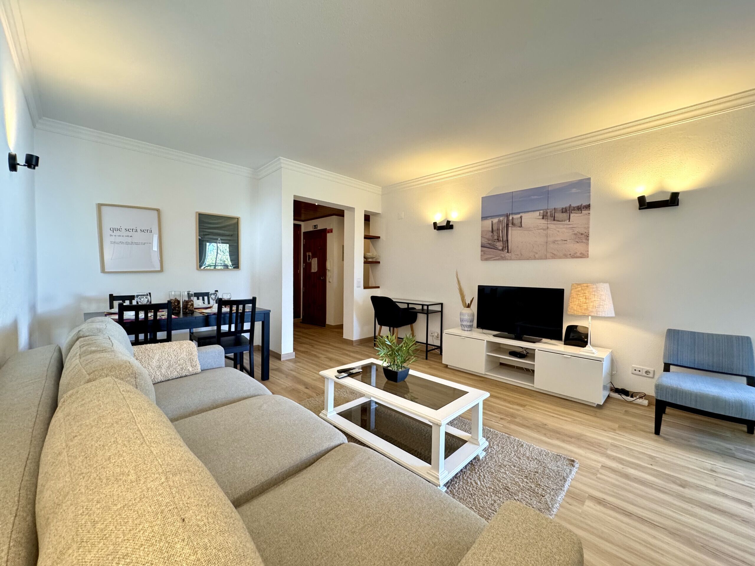A modern living room with a sofa, coffee table, TV, and artwork on the walls.