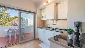 A modern kitchen with a sliding glass door leading to a balcony, a microwave, and a coffee machine. - Vilamoura Cosy 2 With Pool by Homing (Loulé)