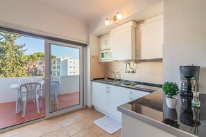 Eine moderne Küche mit einer Schiebeglasdoor zu einem Balkon, einer Mikrowelle und einer Kaffeemaschine.