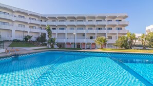 A swimming pool with a geometric tile pattern, surrounded by a building with multiple balconies and a flat roof. - Vilamoura Cosy 2 With Pool by Homing (Loulé)