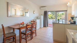 A compact kitchen with a dining table, chairs, a refrigerator, and a small island. - Vilamoura Cosy 2 With Pool by Homing (Loulé)