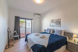 Ein Hotelzimmer mit Bett, Nachttisch, Sessel, einem Balkon mit Blick und einem Bild an der Wand.