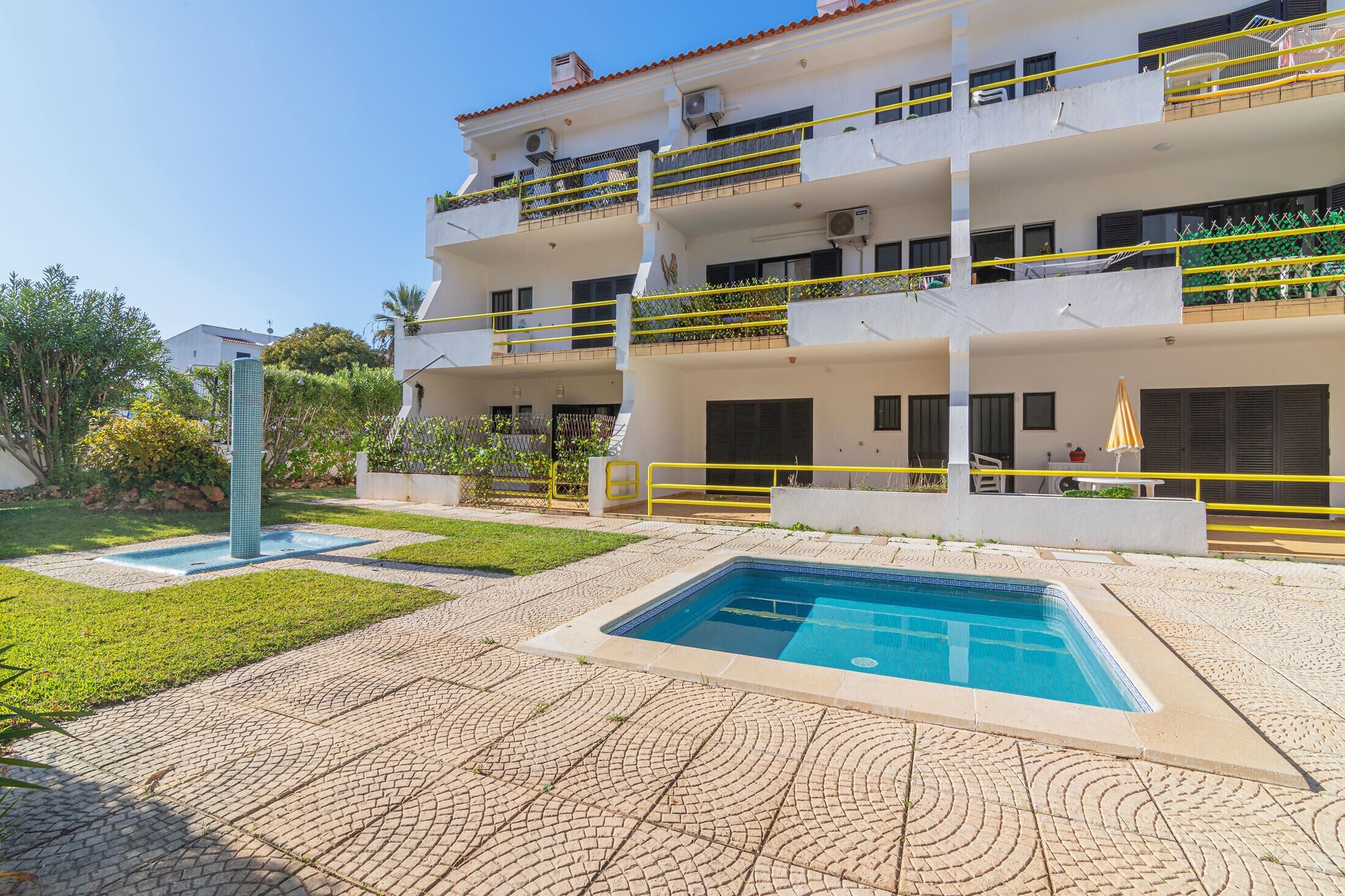 A multi-story building with a swimming pool, outdoor seating, and a well-maintained garden.