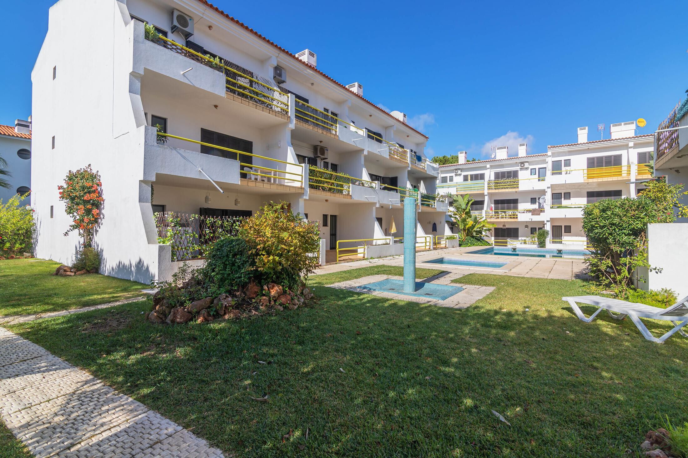 Un immeuble résidentiel à plusieurs étages, doté de balcons, d’une piscine et d’un espace jardin.