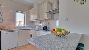 A kitchen with white cabinets, a granite countertop, a dishwasher, a washing machine, and a fruit bowl. - Praia DA Rocha Central With Pool (Portimão)