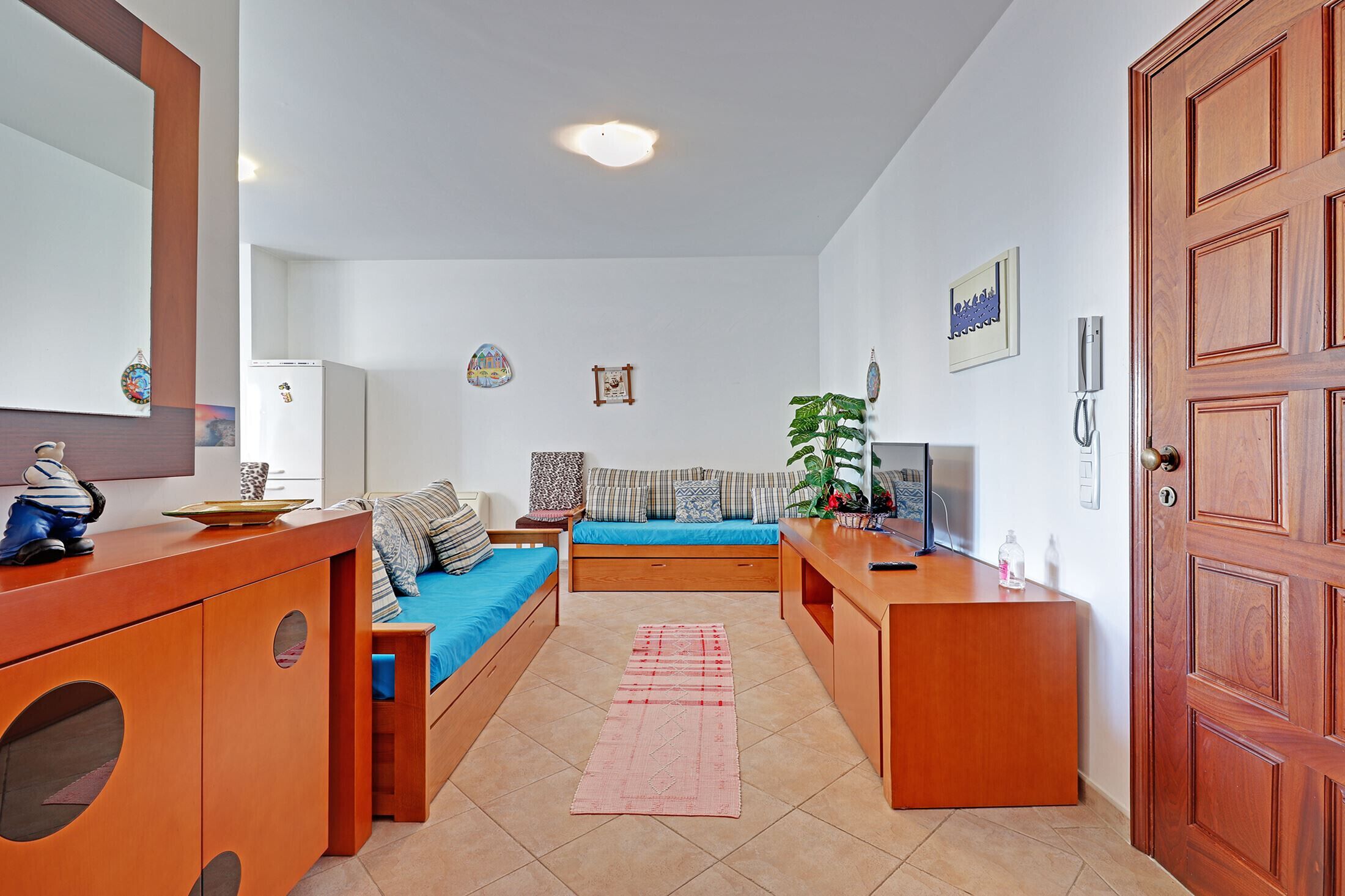 A modern, well-lit room with a sofa bed, a wooden desk, a mirror, and a door.