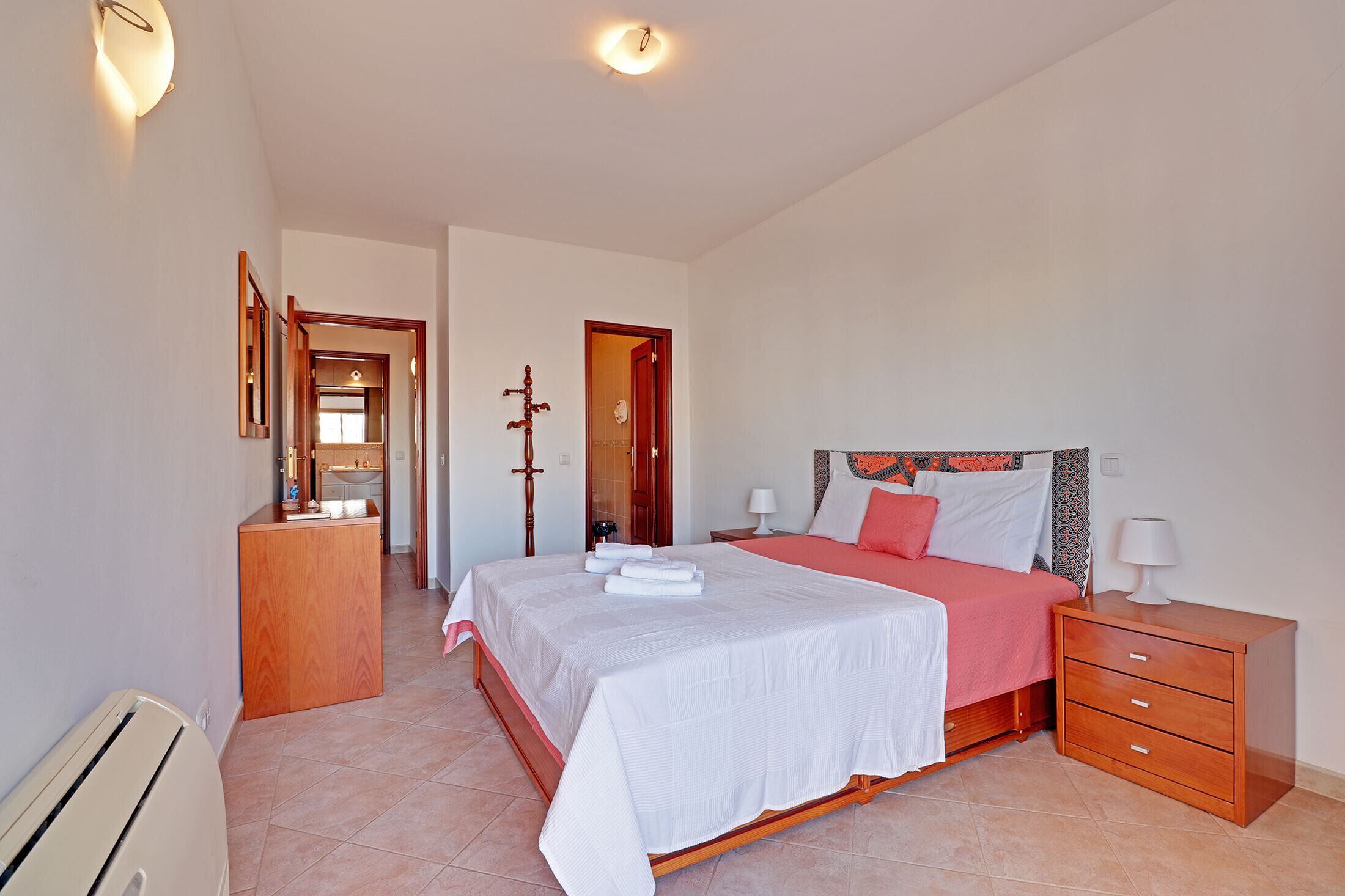 Un dormitorio con cama, mesita de noche y cómoda de madera.