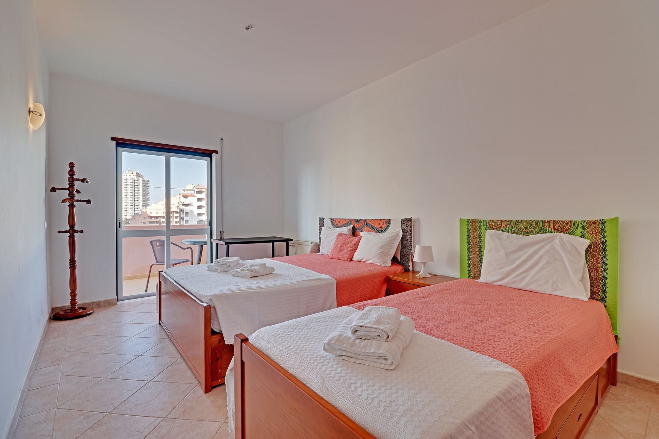A hotel room with two beds, a balcony, and a view of the city.