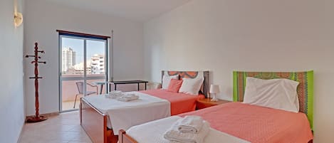 A hotel room with two beds, a balcony, and a view of the city.