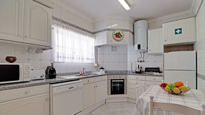 A kitchen with white cabinets, a microwave, a toaster, a sink, and a fruit bowl on the table. - Portimão Solar DO VAU With Pool (Portimão)