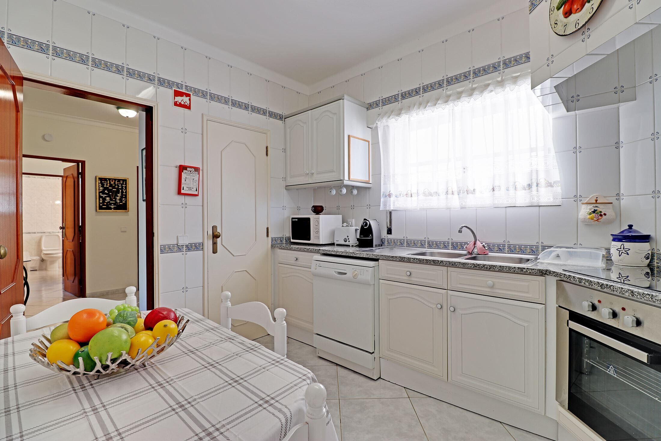 A kitchen with white cabinets, a microwave, a toaster, and a sink.