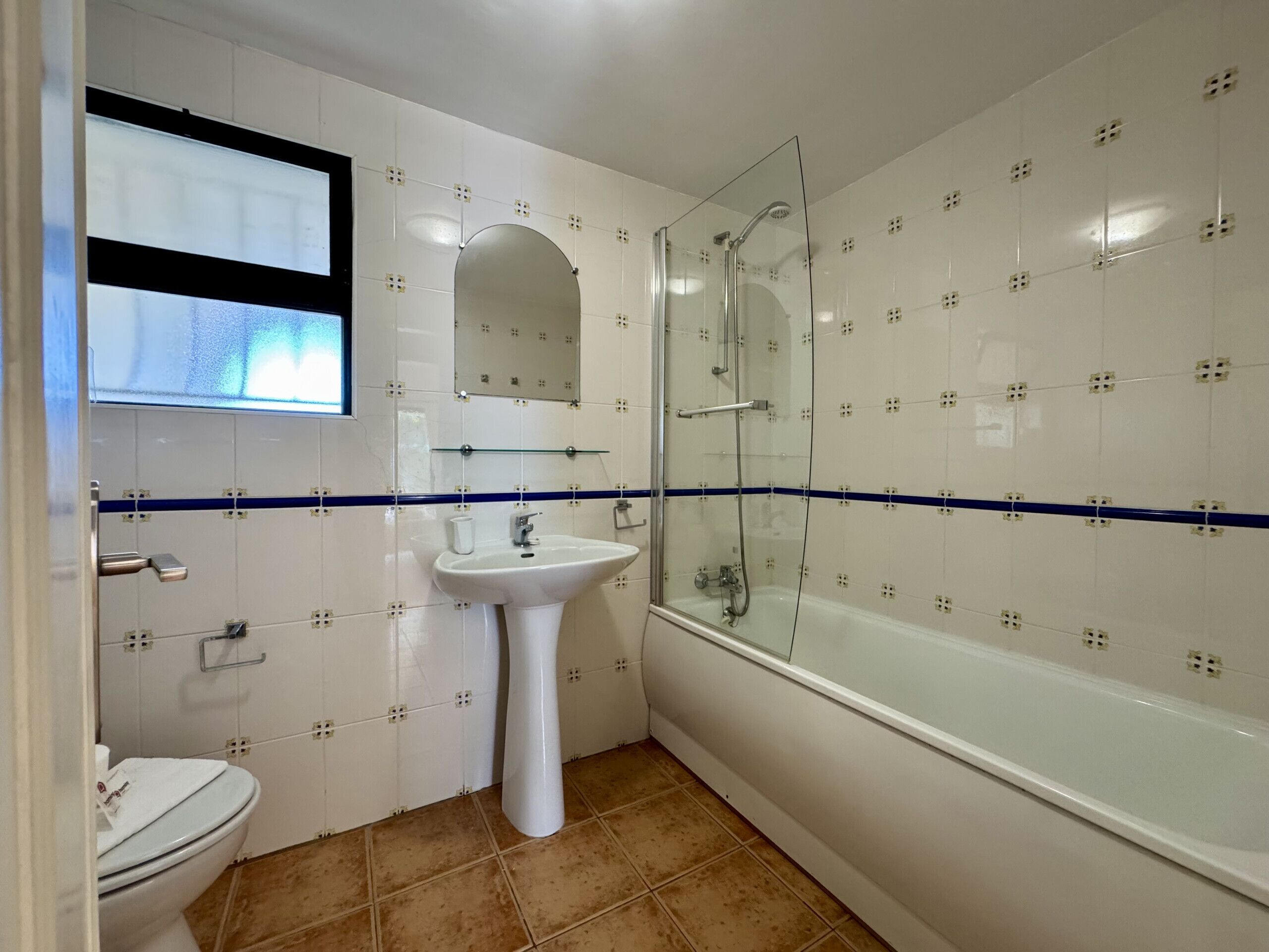A bathroom with a toilet, sink, mirror, shower, and bathtub.