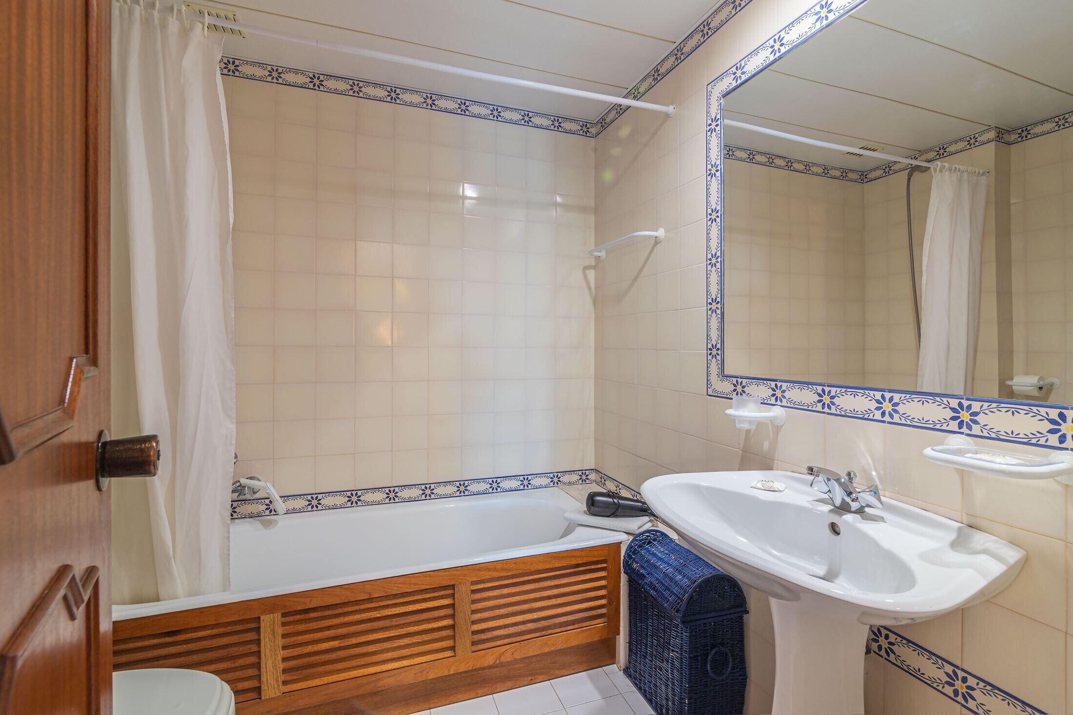 Un baño con bañera, lavamanos y espejo.