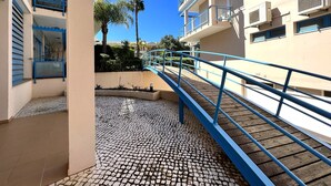 Ein Gebäude mit einer gefliesten Terrasse, einem blauen Geländer und blauem Himmel.