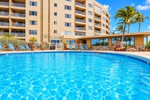 A swimming pool with lounge chairs and a building with balconies in the background. - Pure Luxury Kihei Rare 3BR Oceanfront Condo Freshly Redesigned Ocean Views (Kihei)