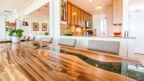 A modern kitchen with wooden cabinets, a stainless steel sink, and a large island with seating. - Pure Luxury Kihei Rare 3BR Oceanfront Condo Freshly Redesigned Ocean Views (Kihei)