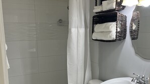 Une salle de bain avec une douche, des toilettes et un lavabo. On y trouve des paniers en osier remplis de serviettes.
